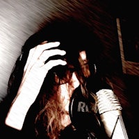 a woman holding her head up in front of a microphone